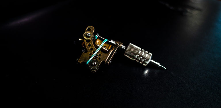 A custom brass tattoo machine on black leather at Idle Hands Tattoo Co. in Jacksonville