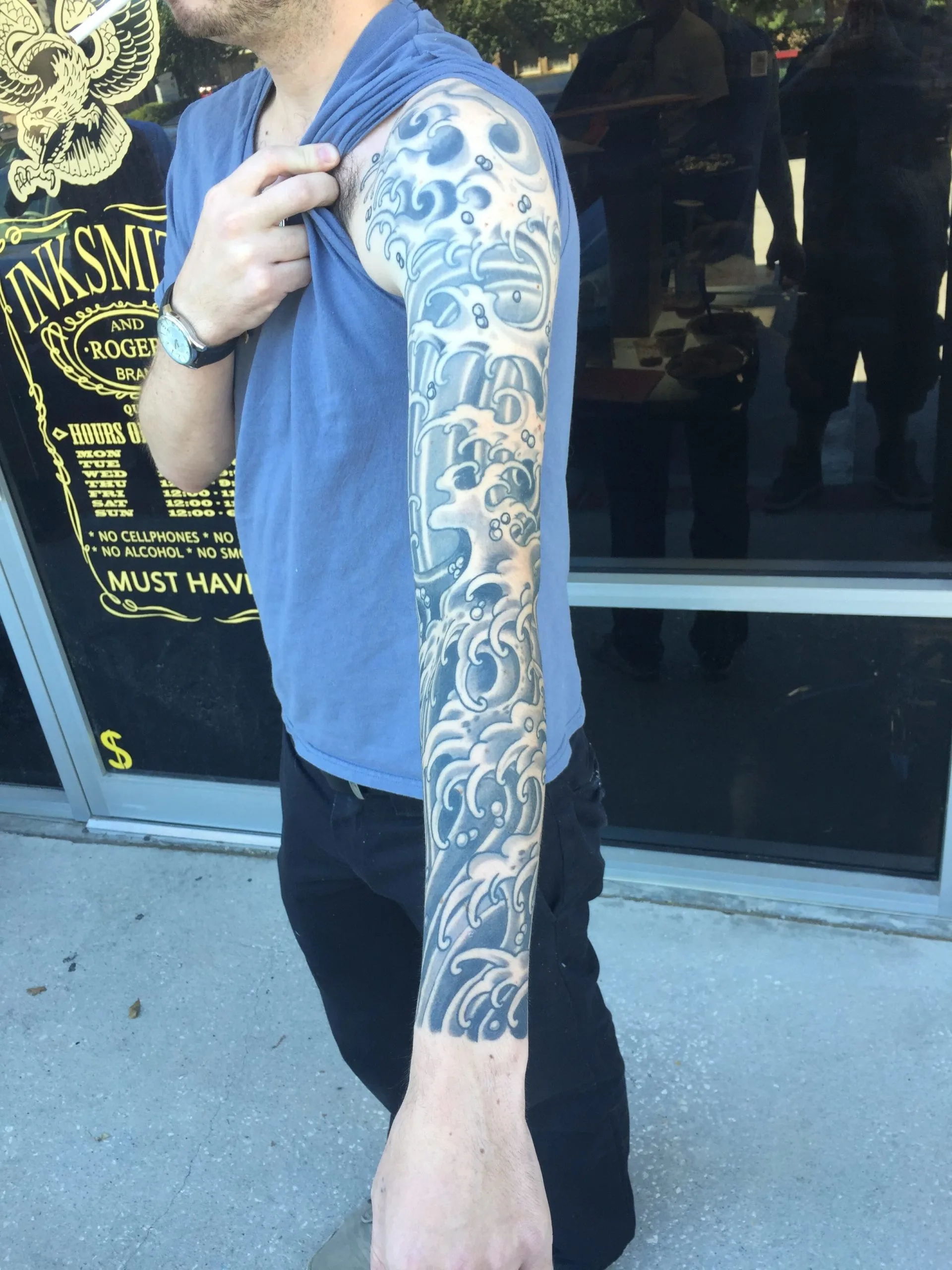 Full arm sleeve with black and grey wave and cloud swirl patterns from shoulder to wrist