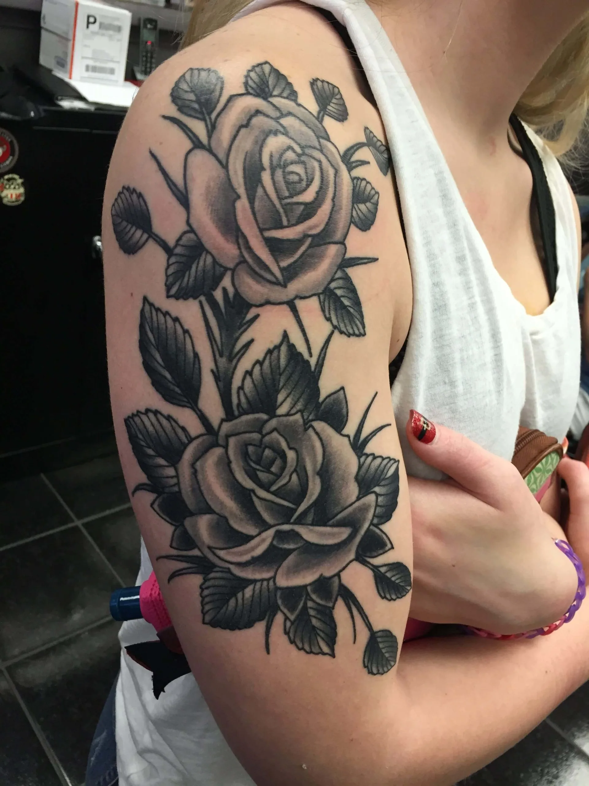 Two black and grey roses with leaves stacked vertically on the upper arm