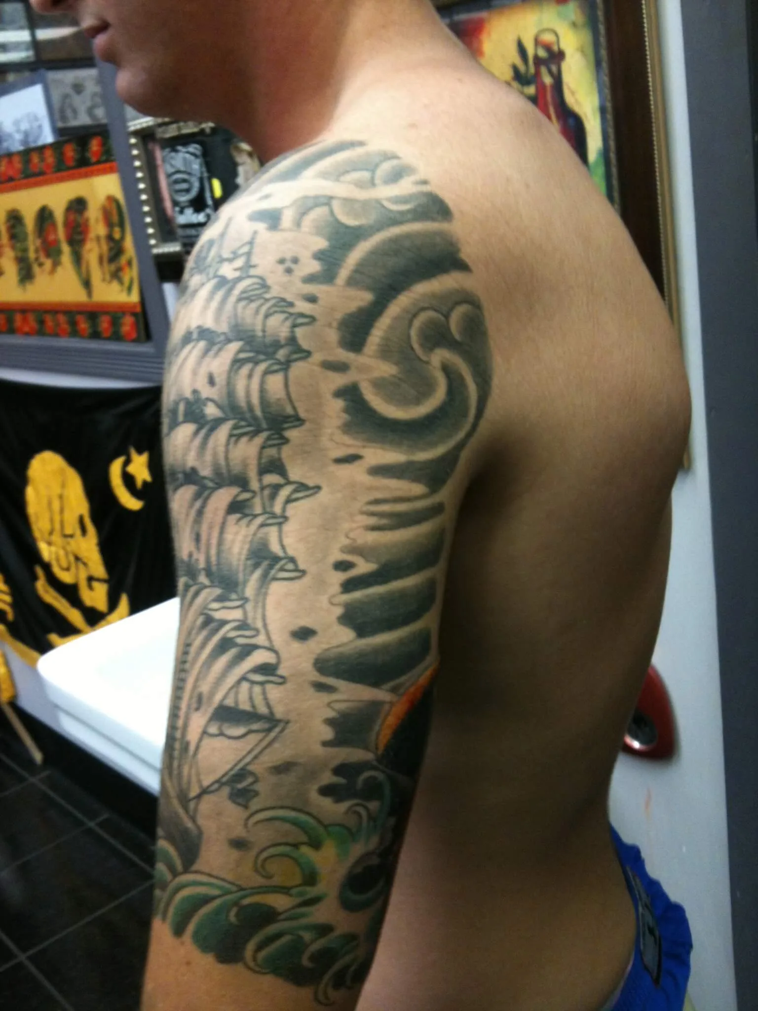 black and grey half-sleeve on the shoulder and upper arm with swirling wave and cloud patterns