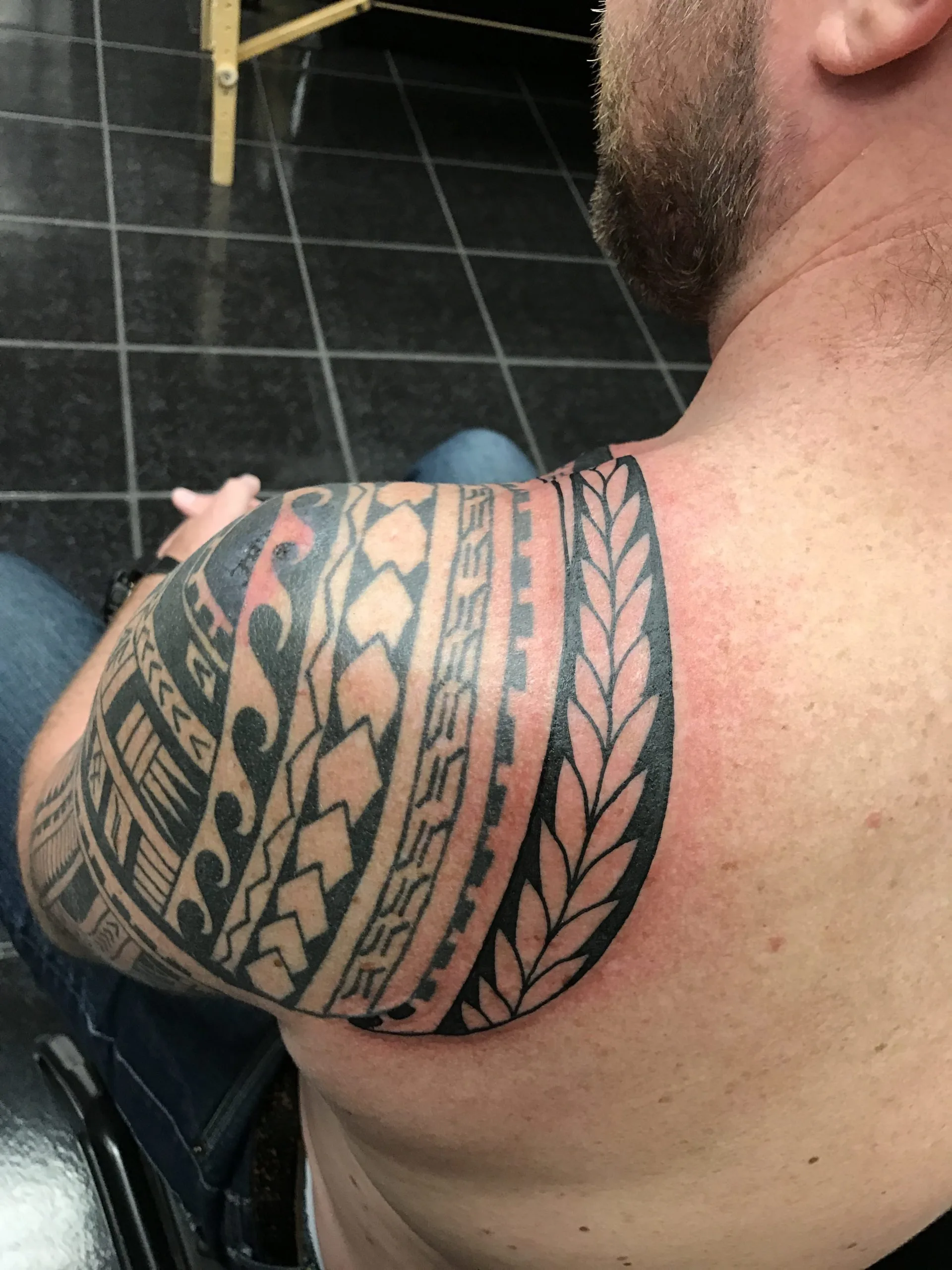 Black tribal geometric banding wrapping across the shoulder and upper arm