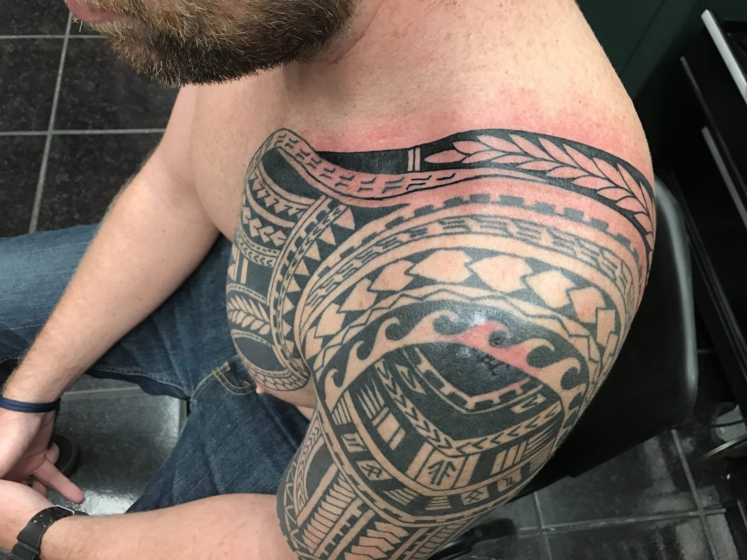 Black tribal geometric pattern on the shoulder cap extending onto the upper arm