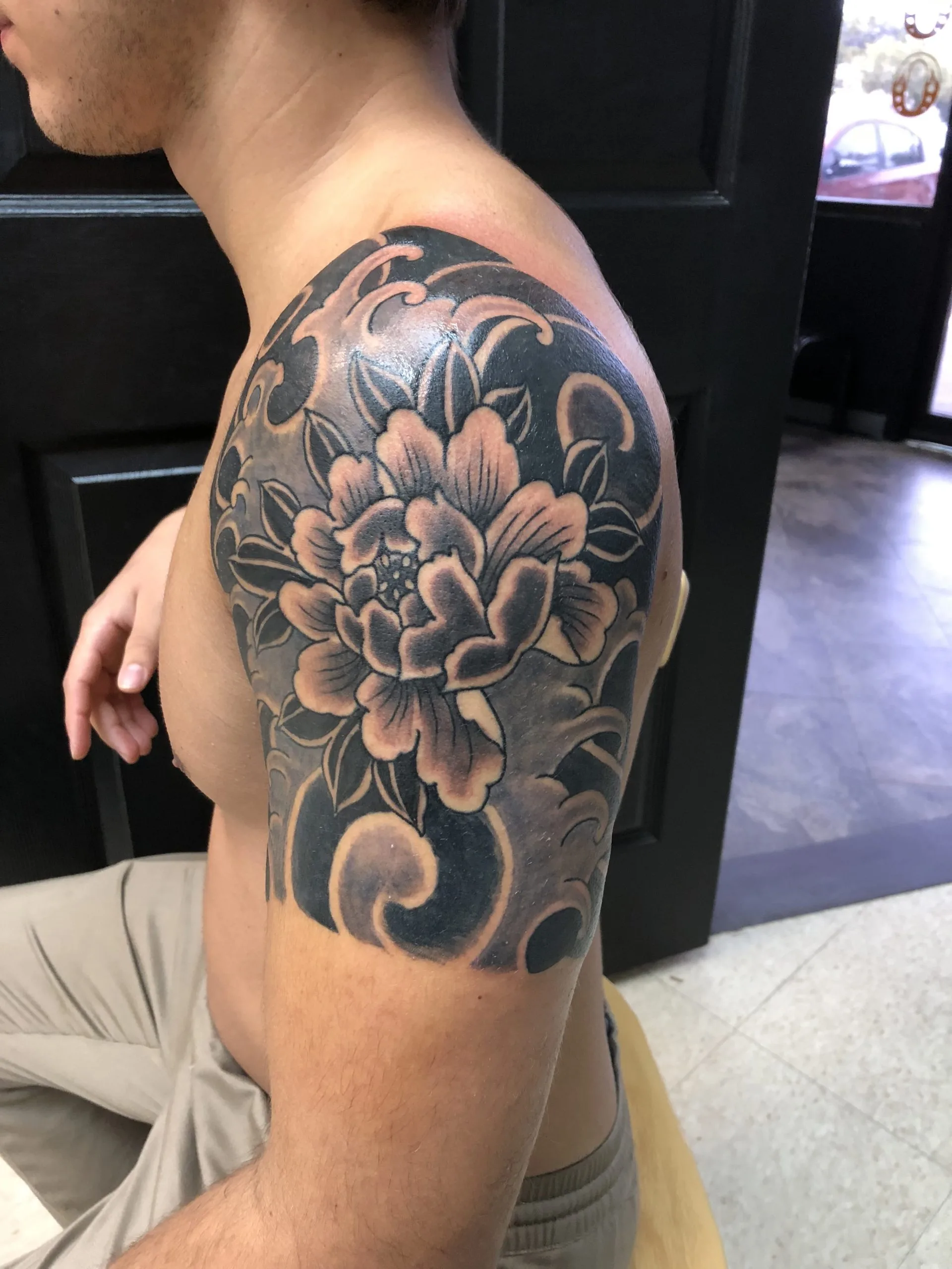 Large grey peony with layered petals on the shoulder, black scrollwork background