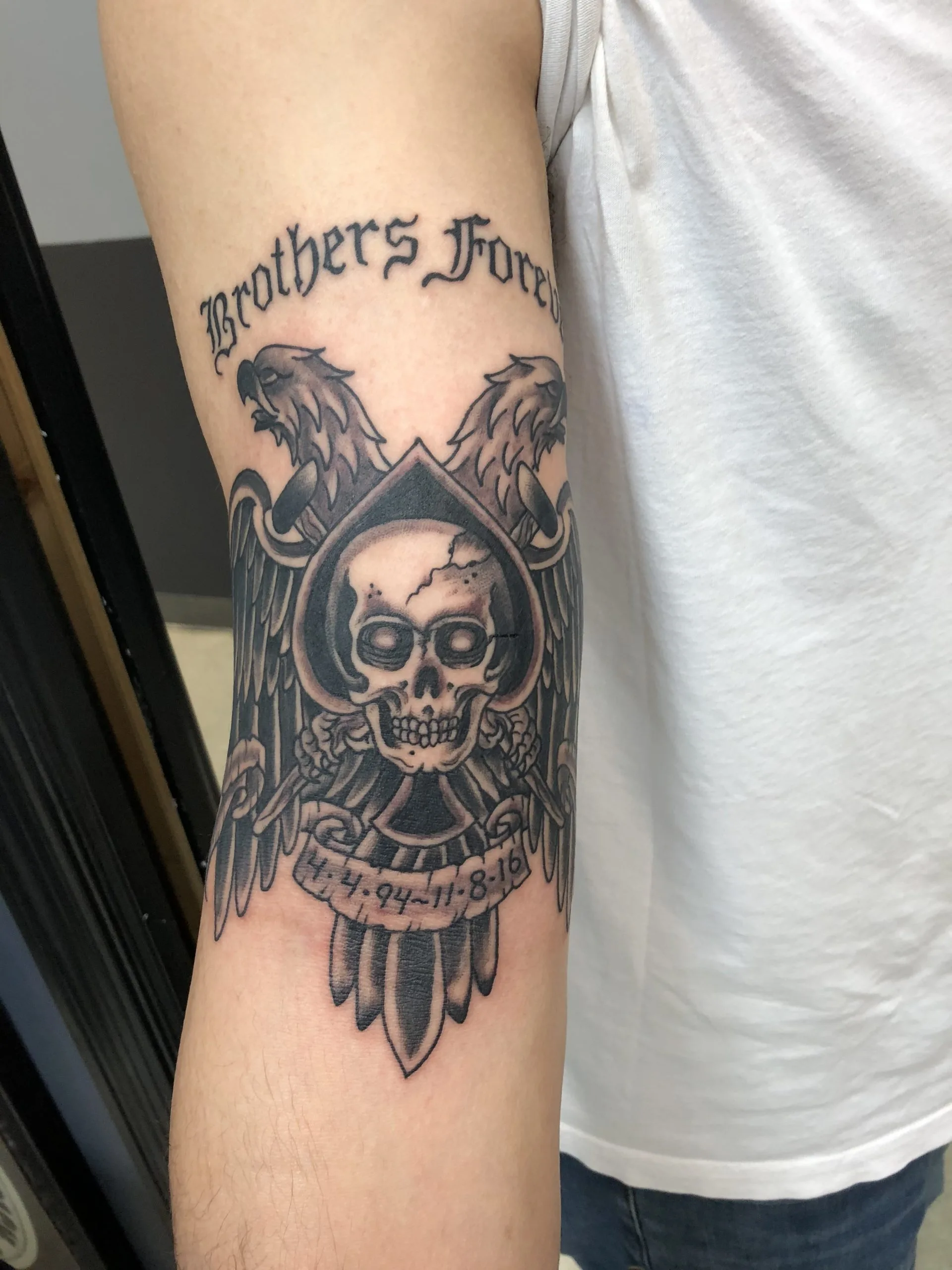 Skull in a spade emblem flanked by eagle heads and wings, with 'Brothers Forever' lettering and dates, forearm, black and grey