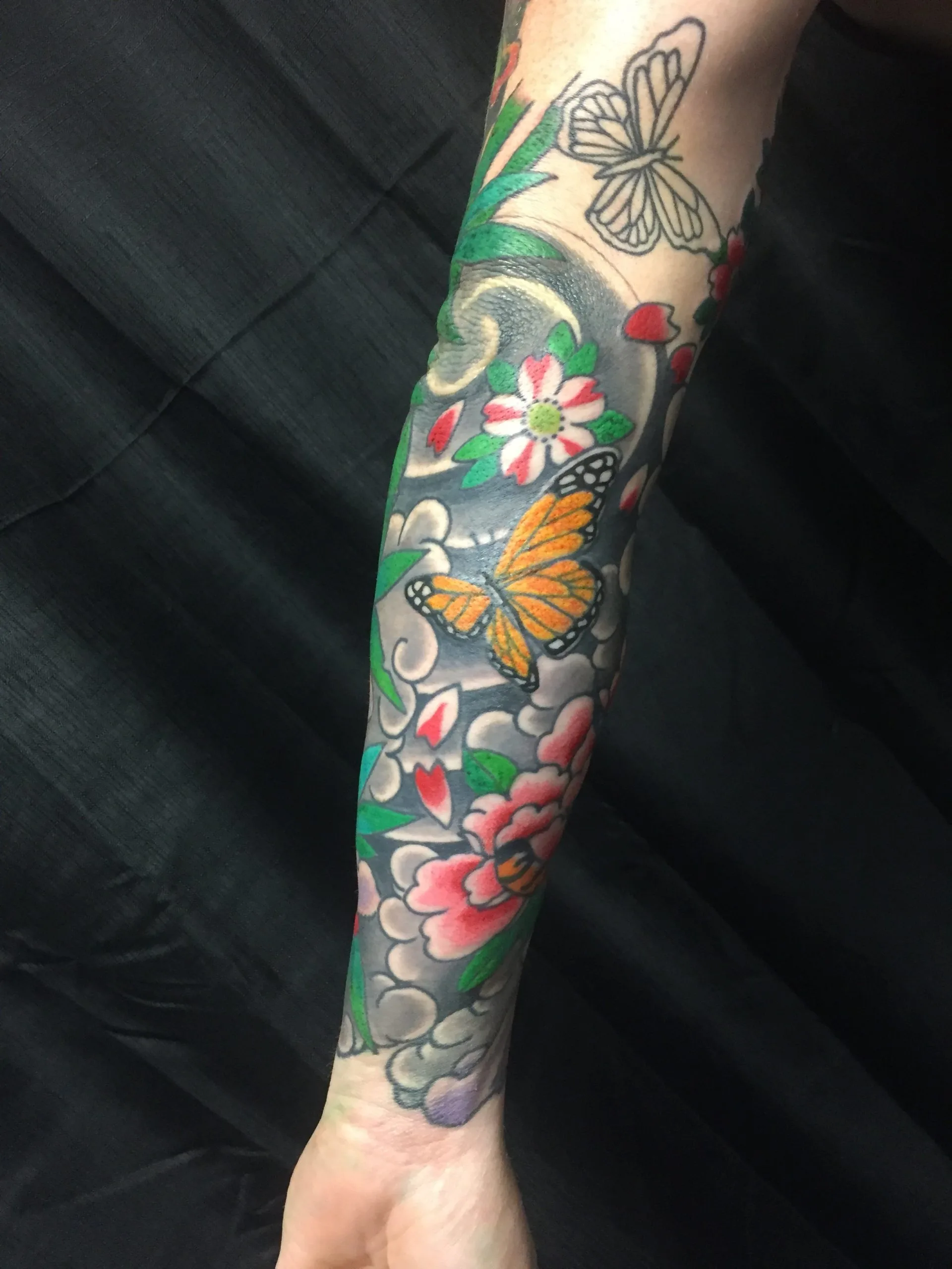 Colour Japanese forearm sleeve with a monarch butterfly, cherry blossom and a pink peony over grey wind bars