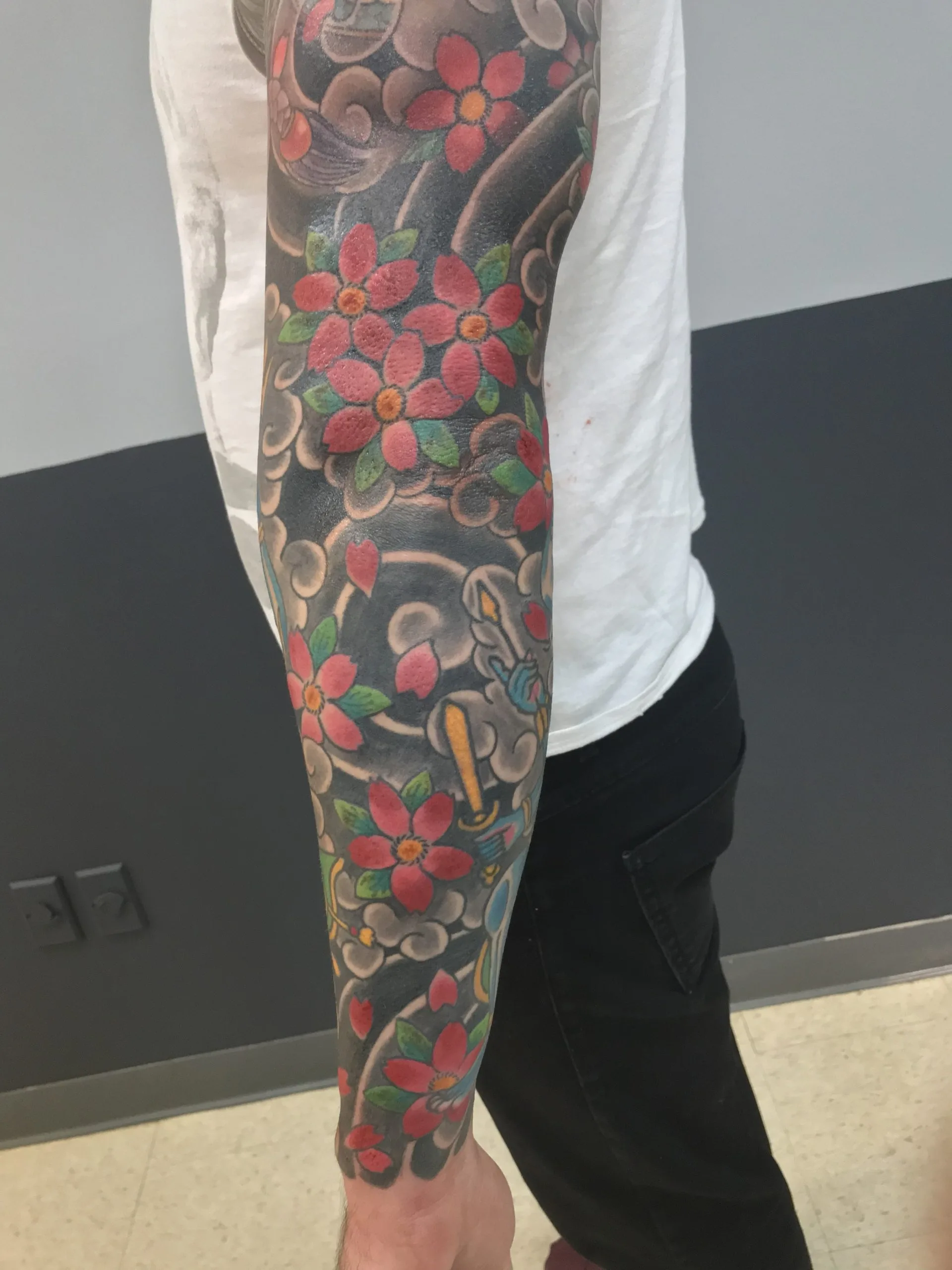 Colour Japanese arm sleeve densely covered in red cherry blossoms over near-black cloudwork
