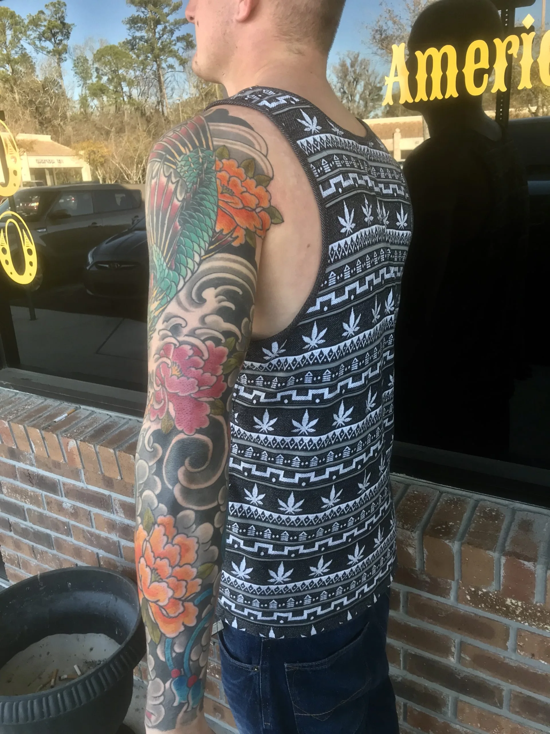 Color full arm sleeve with a green and red koi, orange peonies, and grey wave-cloud patterns down to the wrist