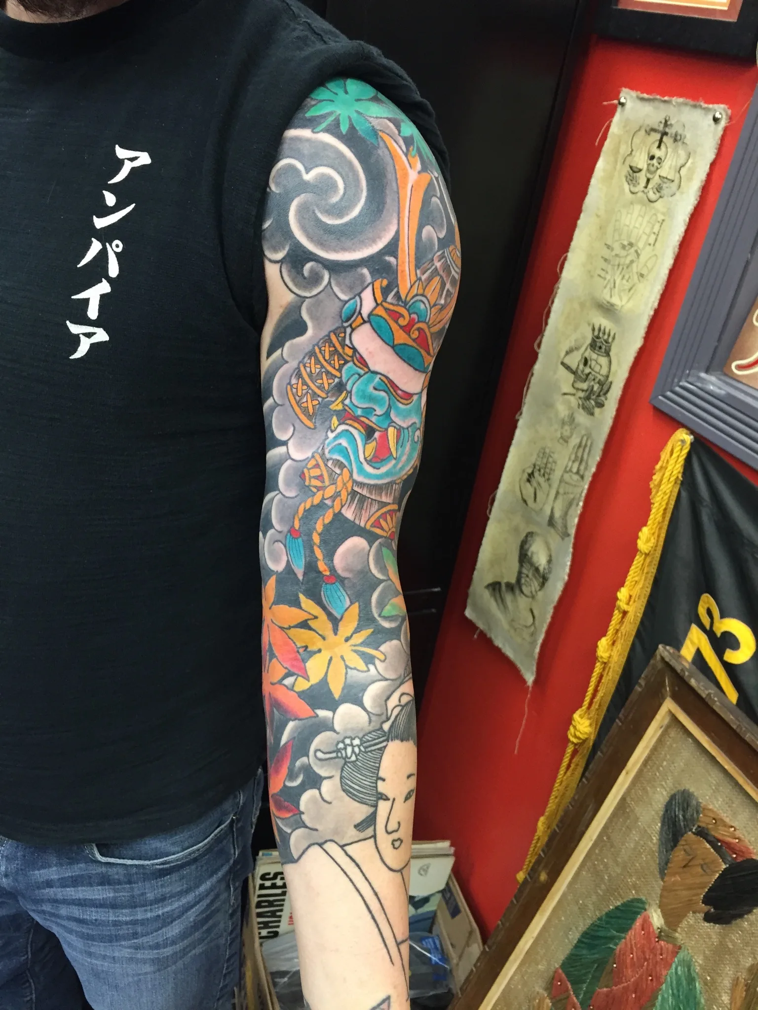 Colour full sleeve with a samurai helmet, grey clouds, orange maple leaves, and an outlined face near the wrist