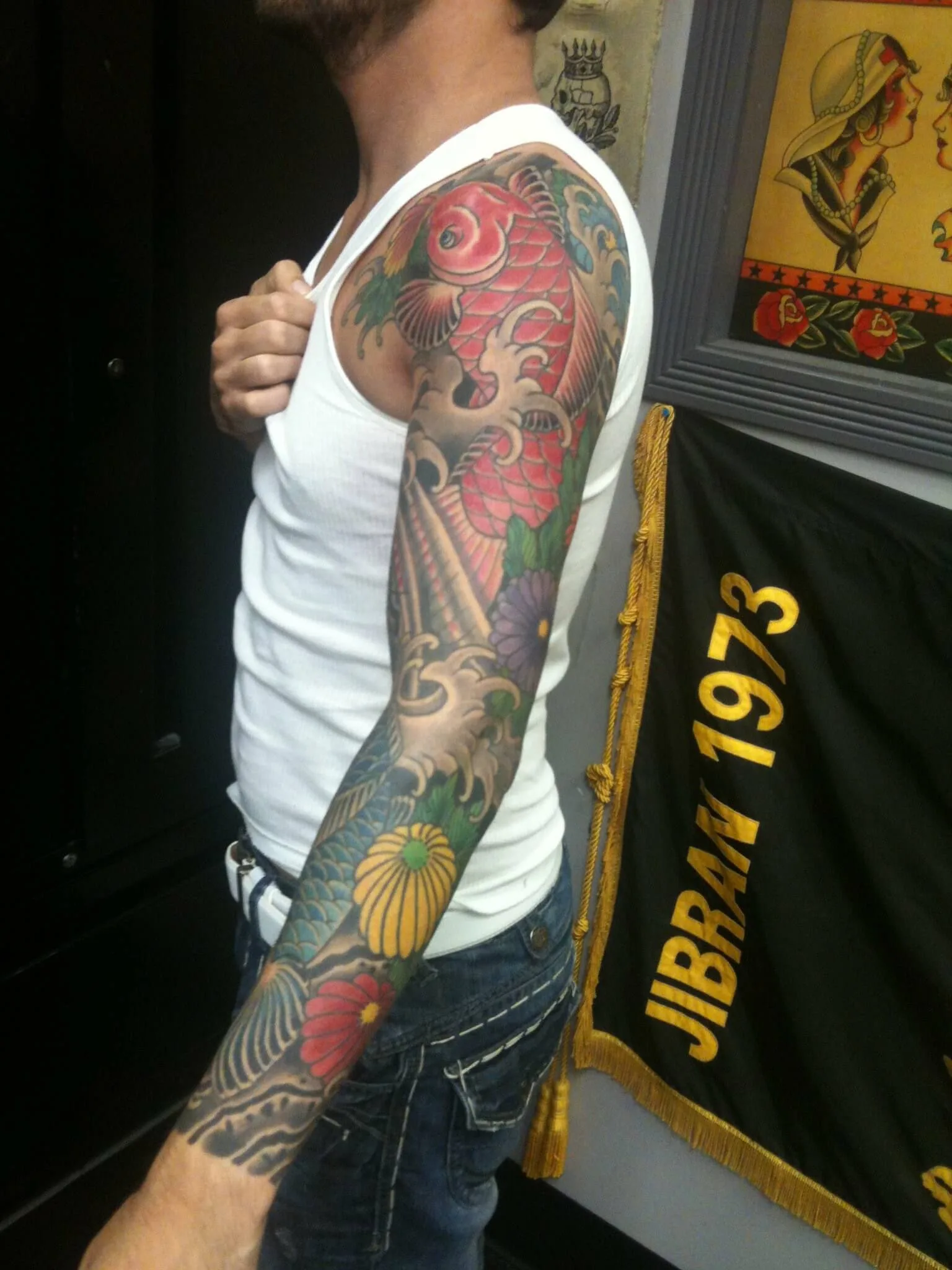 Colour full sleeve with an ascending red koi fish, purple and yellow chrysanthemums, and grey wave patterns