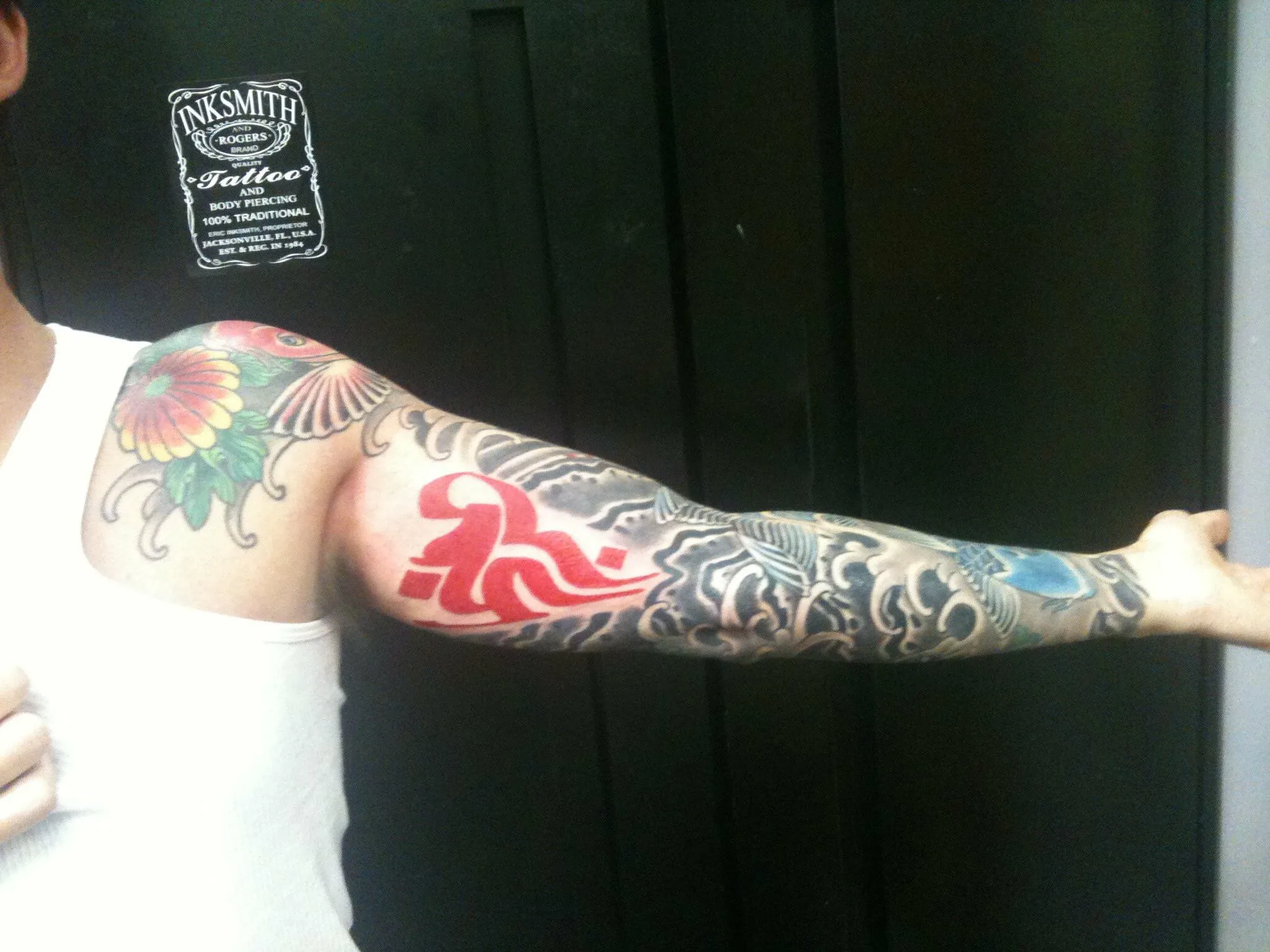 Upper arm with a red stylized Japanese character over black and grey wave scrollwork