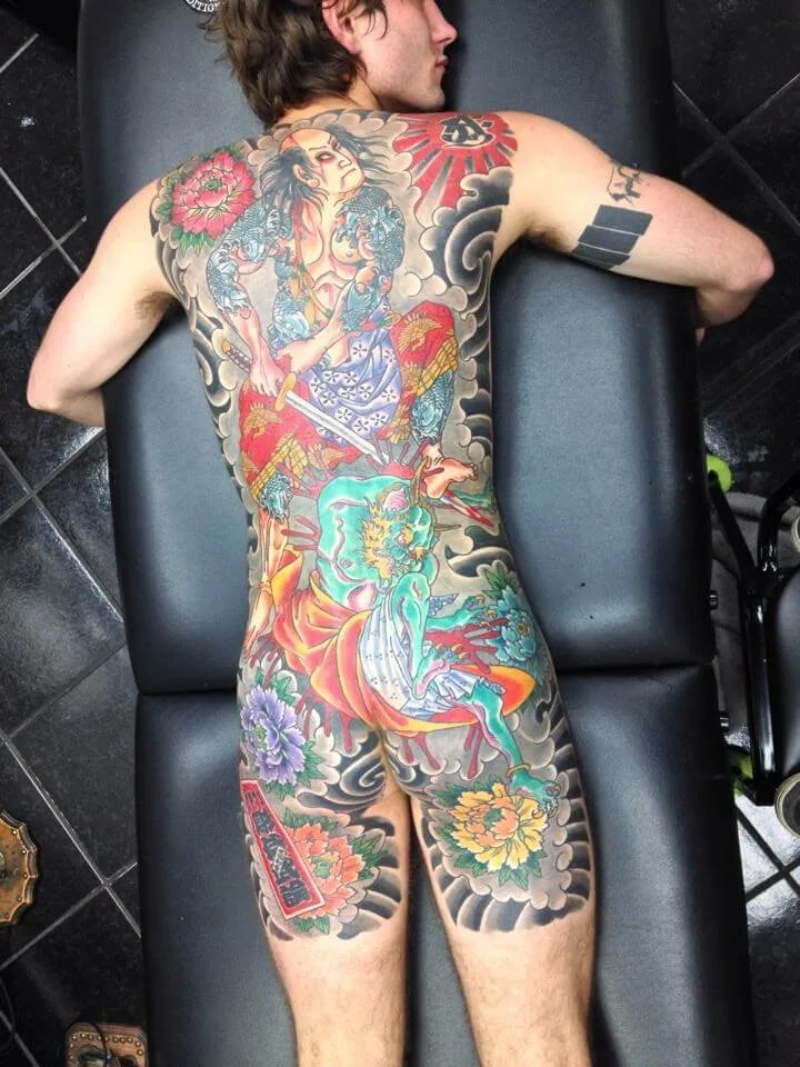 Colour full back piece with a sword-wielding figure, a teal serpent creature, red armor, and peonies