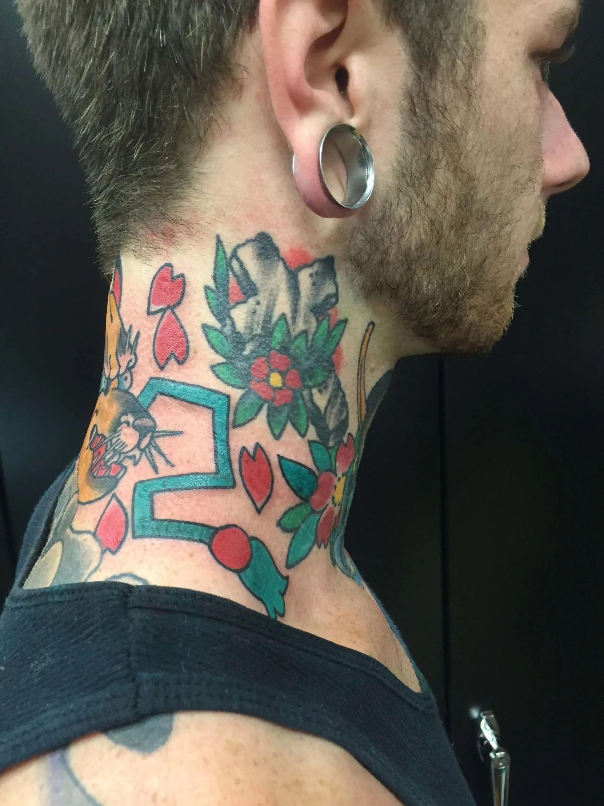 Color neck tattoo with red hearts, pink flowers, green leaves, and a teal abstract shape including a small animal face