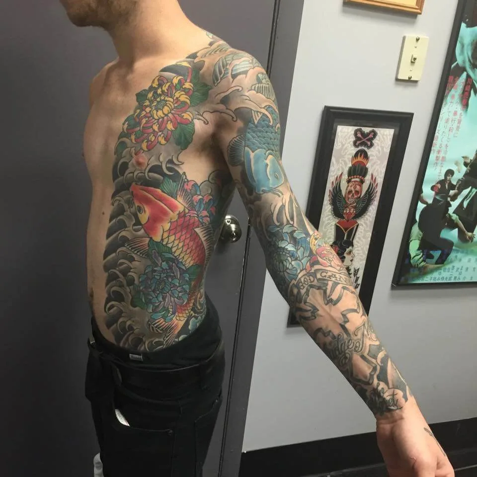 Color side and full-arm piece with a red koi and yellow chrysanthemum on the ribs, continuing into a black and grey wave sleeve