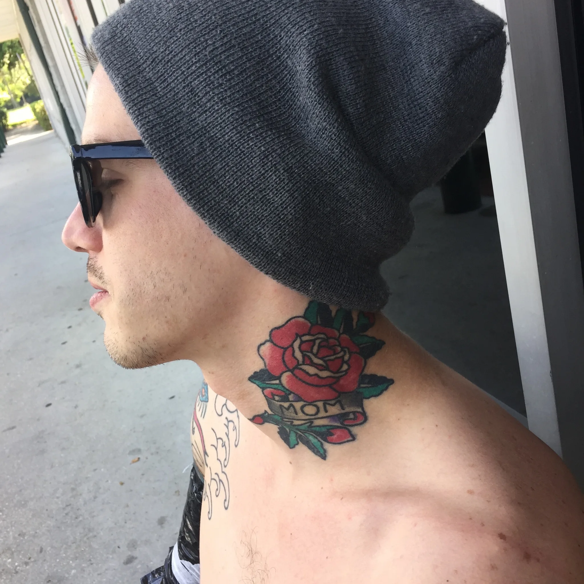 Red rose neck tattoo with a MOM banner and green leaves in traditional style