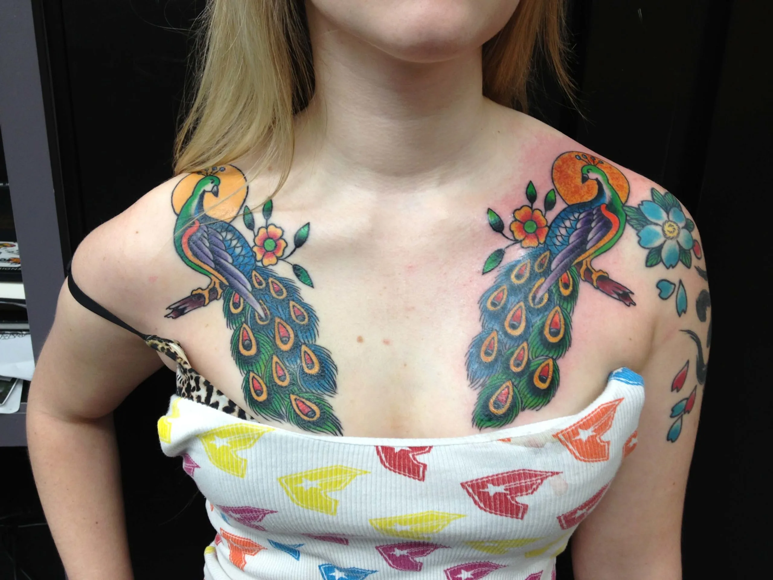 Pair of peacocks facing each other with spread fan tails and flowers on the chest
