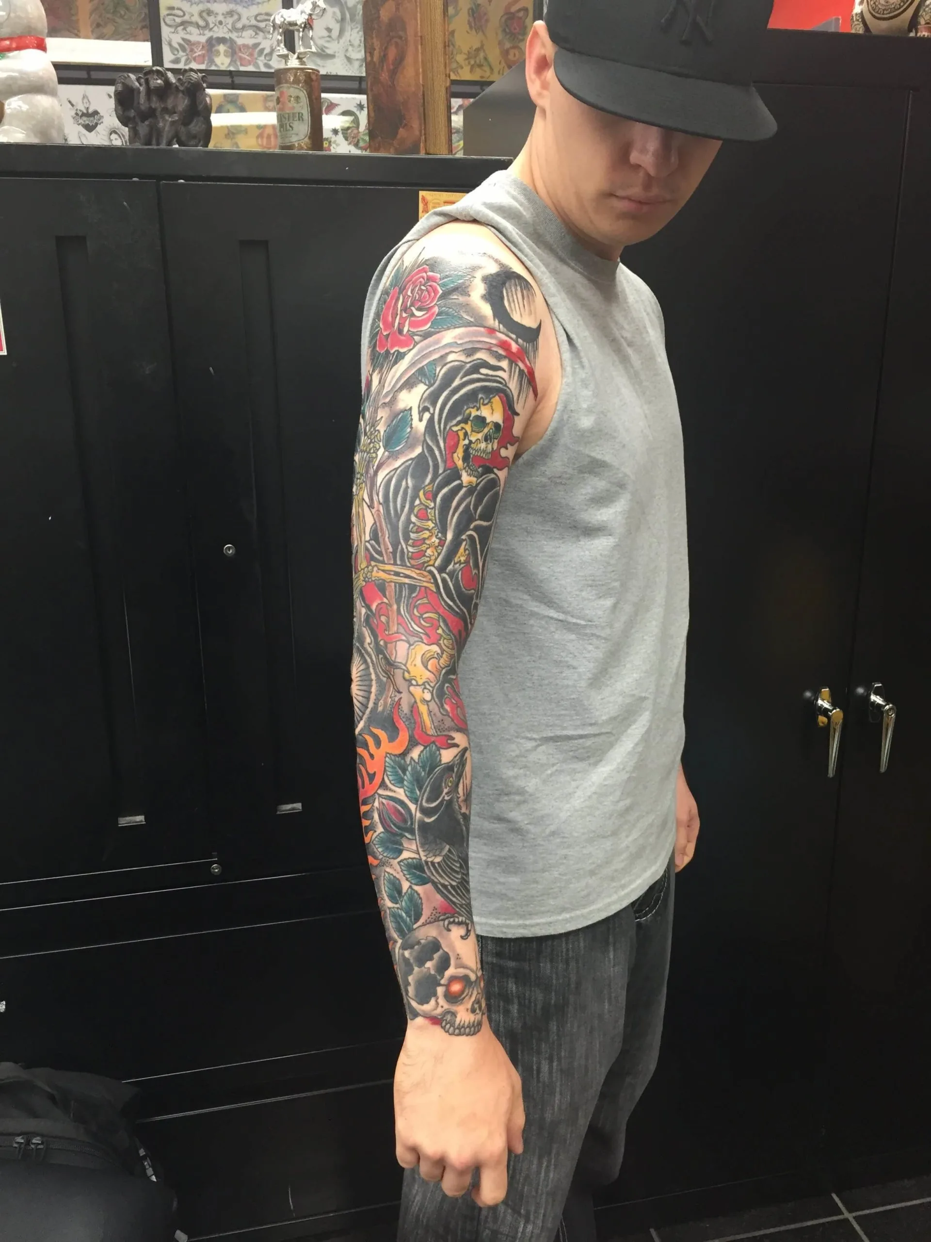 Colour full arm sleeve with a hooded skull figure, red roses, and flames