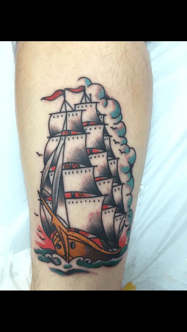Color calf tattoo of a traditional sailing ship with white sails, red flags, and teal wave crests