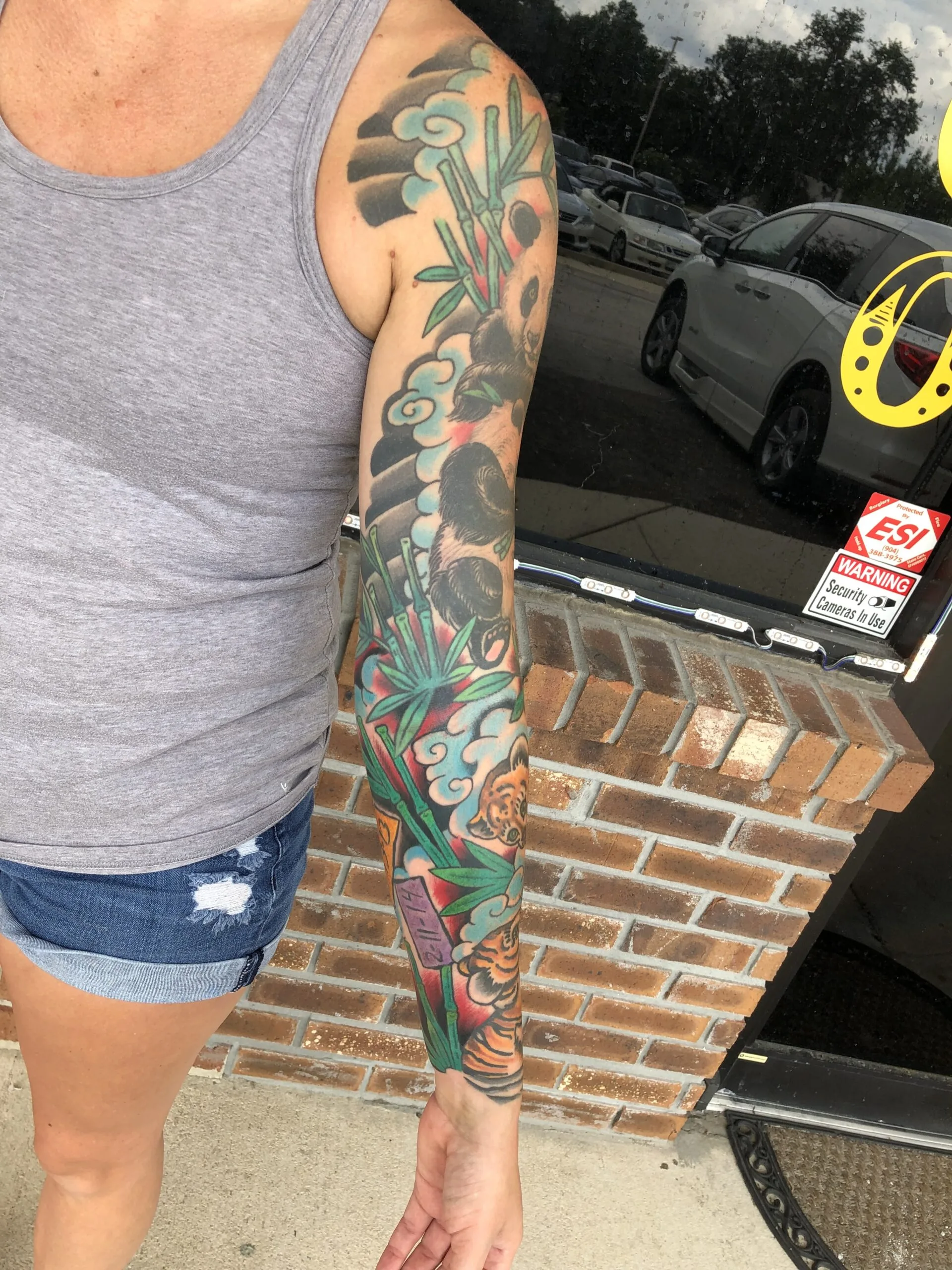 Bamboo and pale blue clouds on the upper arm continuing into a colorful lower sleeve with a creature face