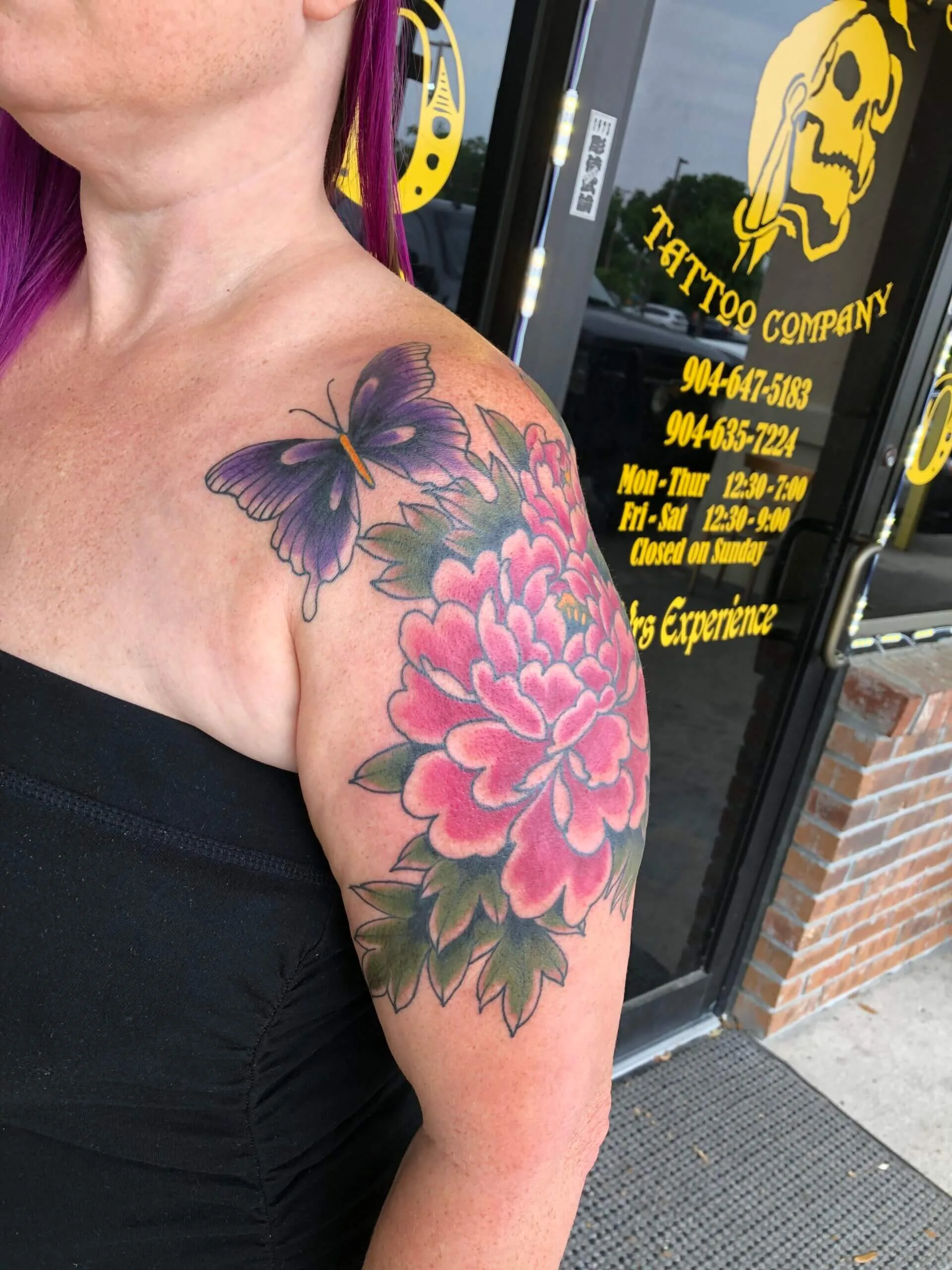 Shoulder and upper arm with a purple butterfly and a large pink peony with green leaves in colour