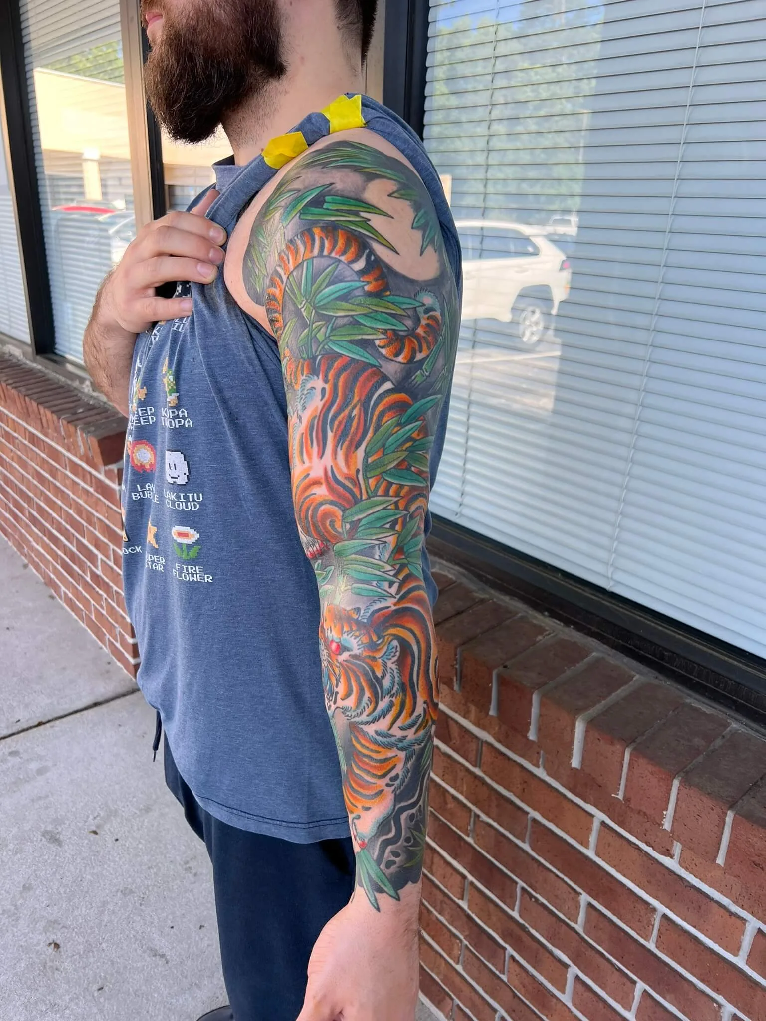 Tiger wrapped around bamboo stalks in orange, black and green, covering the shoulder to full arm
