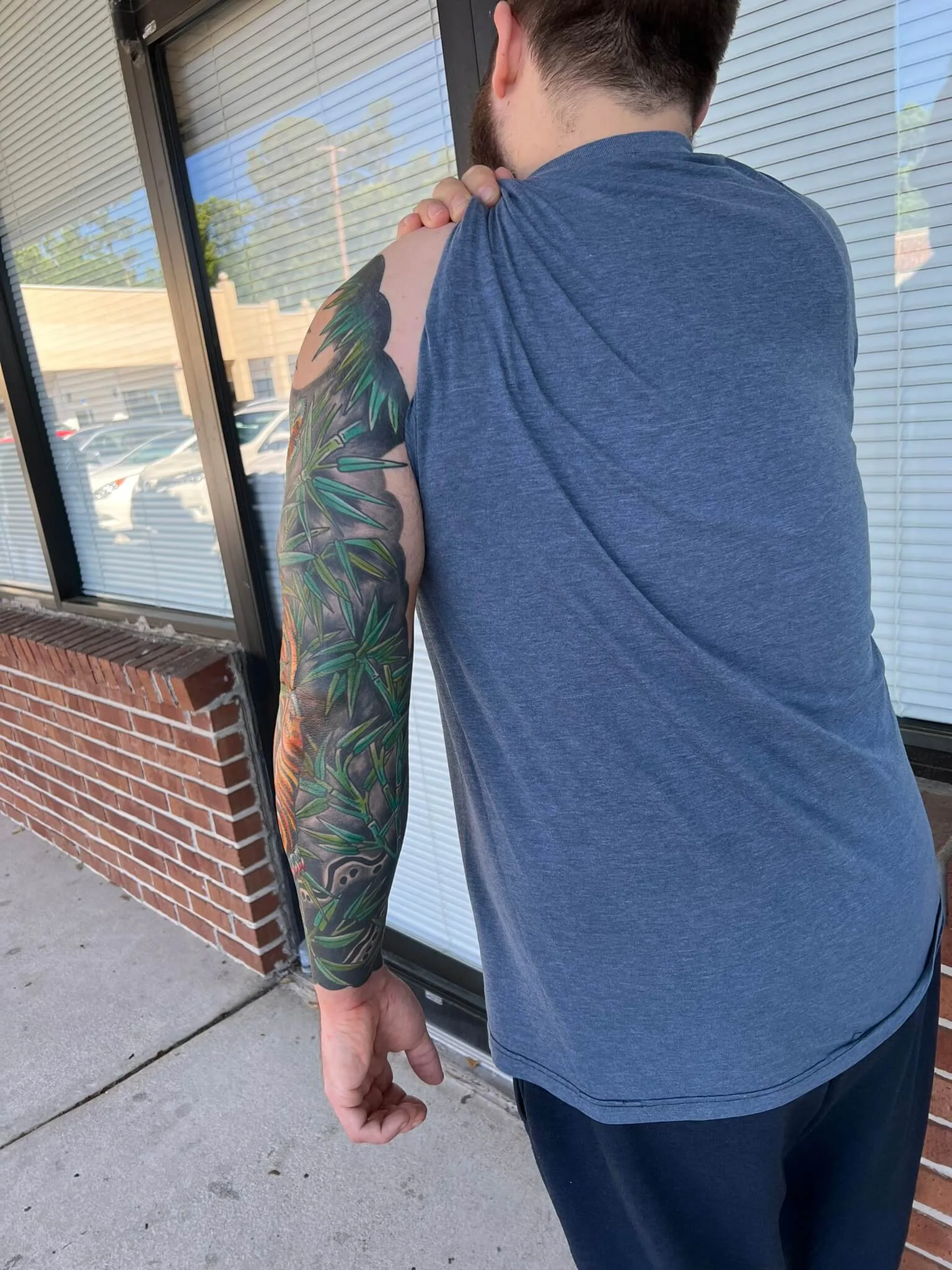 Color arm sleeve with green bamboo leaves over black and grey shading and a tiger's orange coloring near the wrist