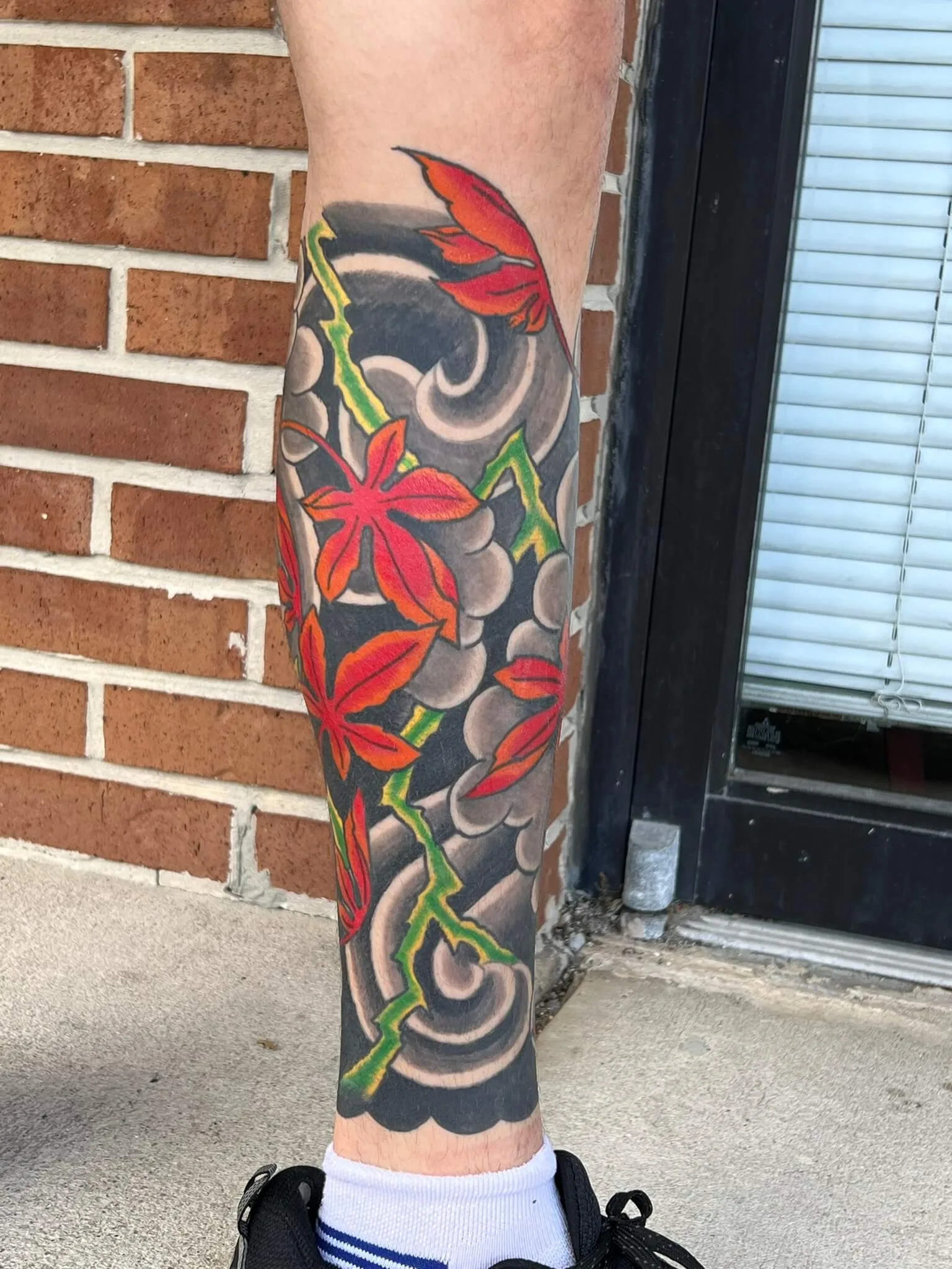 Red maple leaves scattered across grey wave-cloud patterns, on the calf