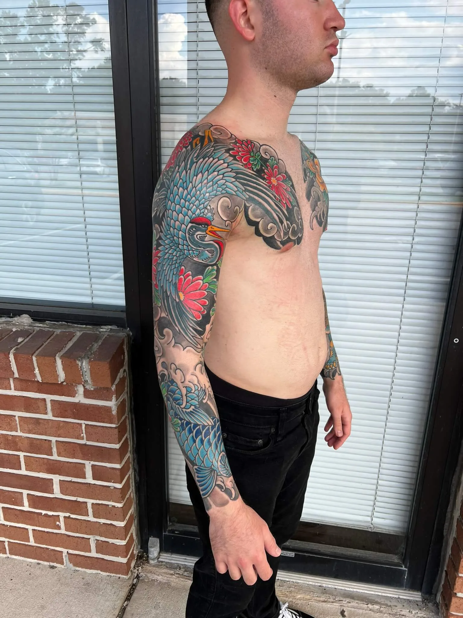 Chest and full arm piece with a large blue-grey crane, red chrysanthemums, and grey cloudwork, in colour