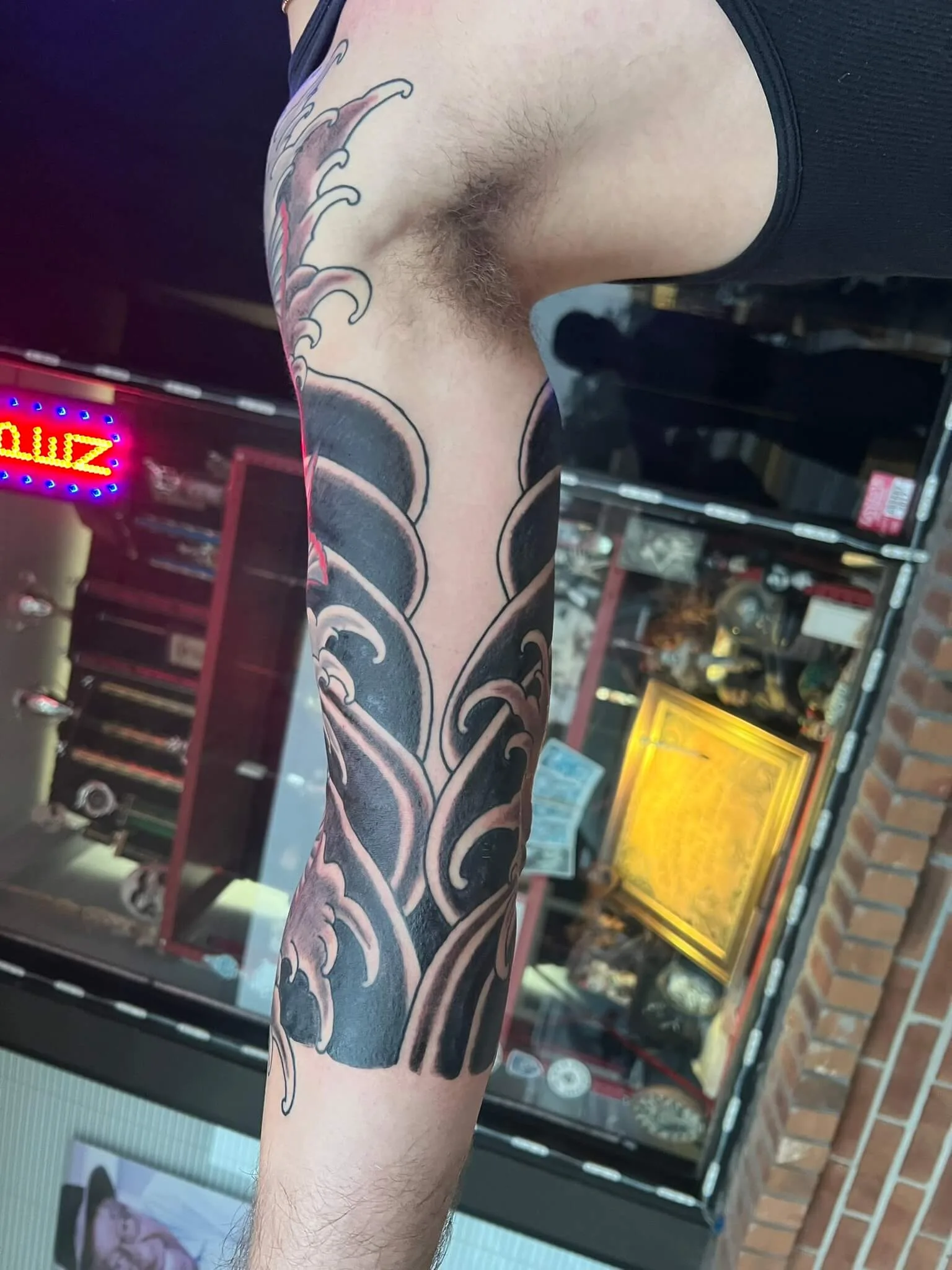 Black and grey wave pattern down the inner arm, underarm to wrist, with a thin red accent line
