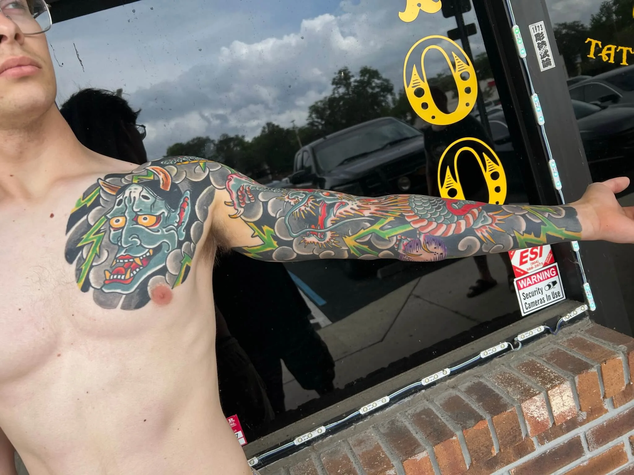 Colour full arm sleeve with a green horned mask at the shoulder and a dragon down the forearm, lightning bolts throughout