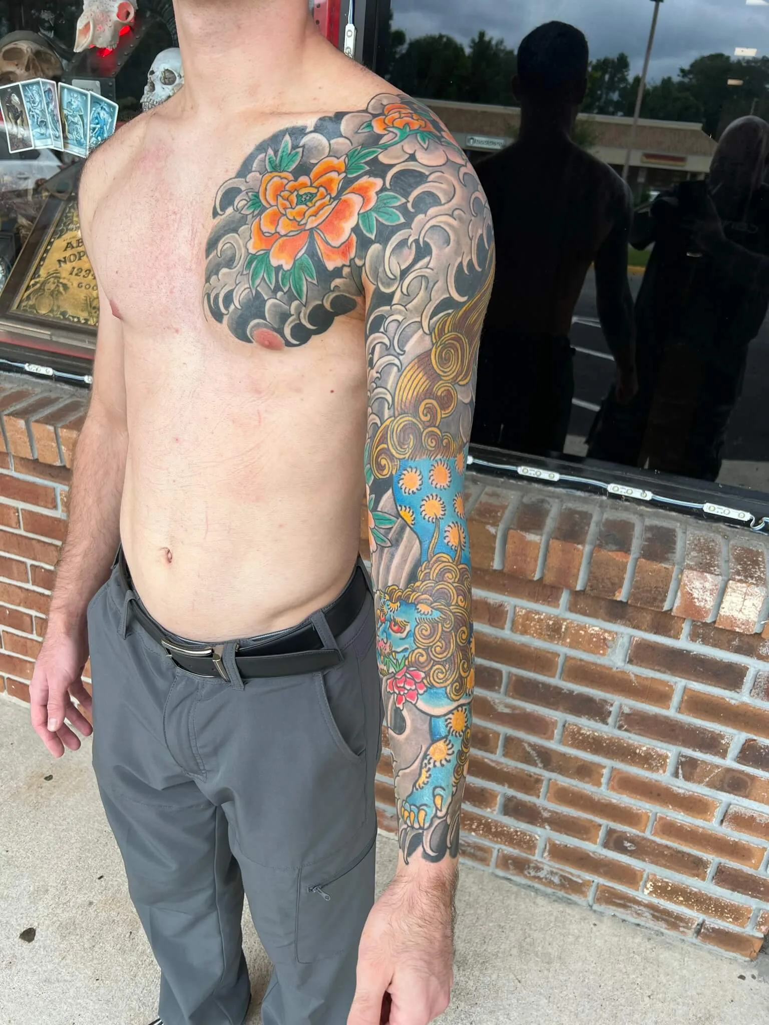 Orange peony chest panel joining a full sleeve with a blue and orange foo dog among grey clouds